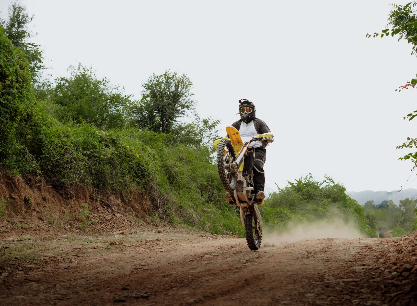 Off-road rider lifting the front wheel on a dirt trail